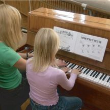 Dziewczynka i prowadząca przy pianinie