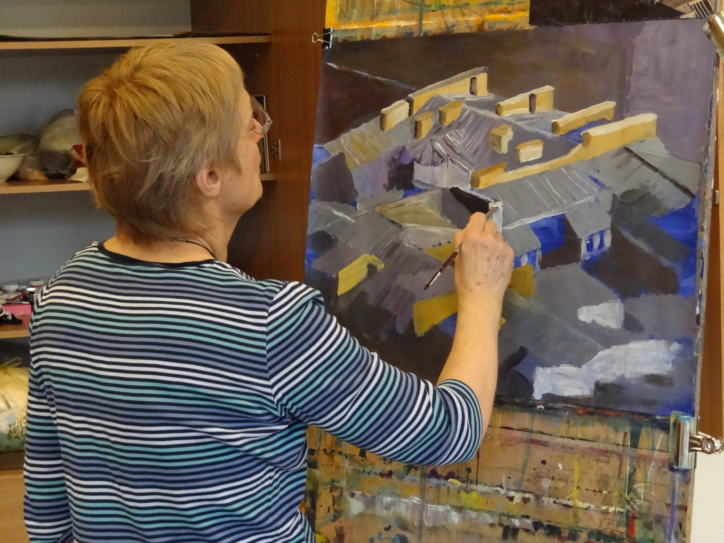 Kobieta maluje obraz w trakcie zajęć