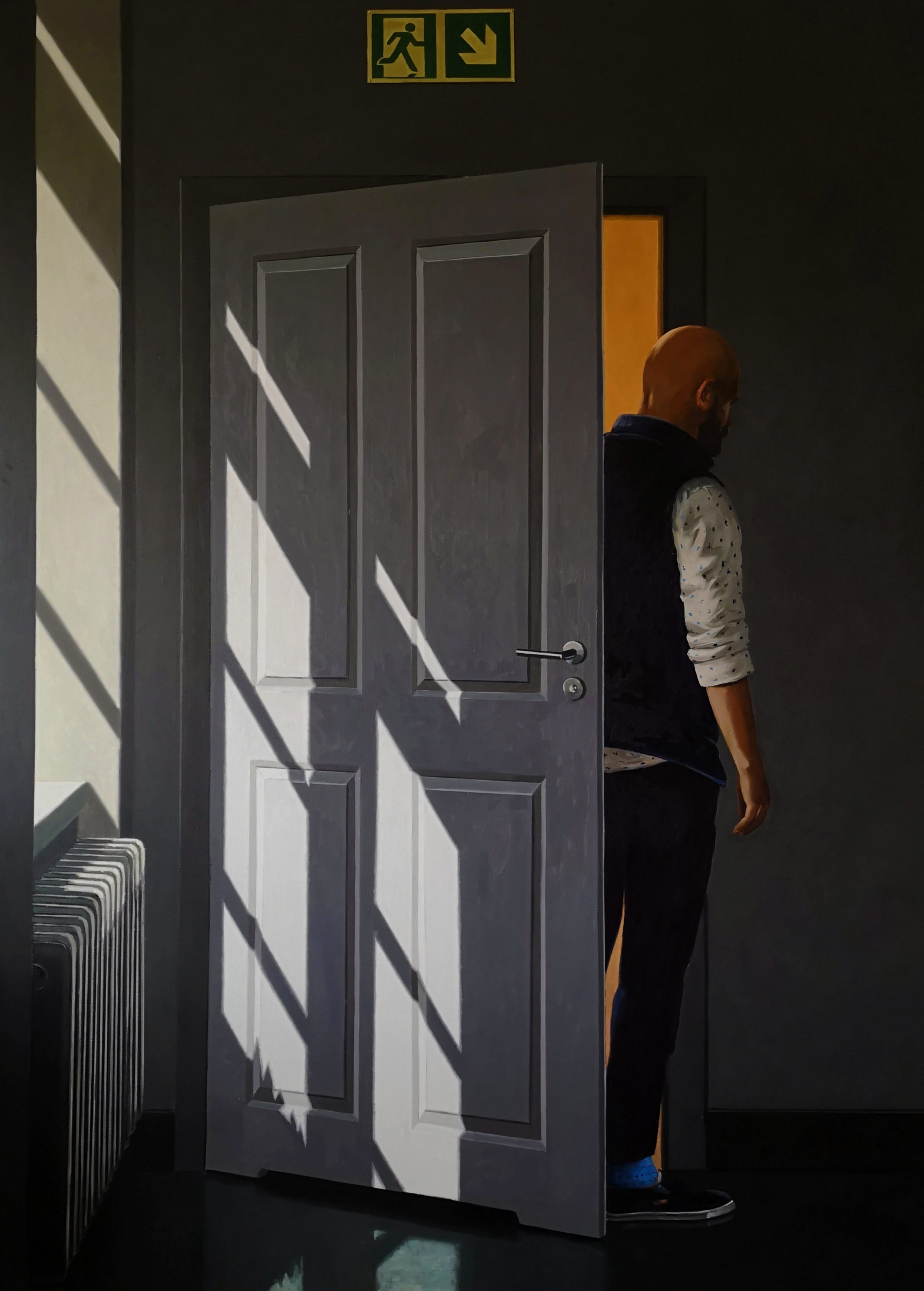 Mężczyzna wychodzący z pokoju przez białe drzwi, stoi tyłem.