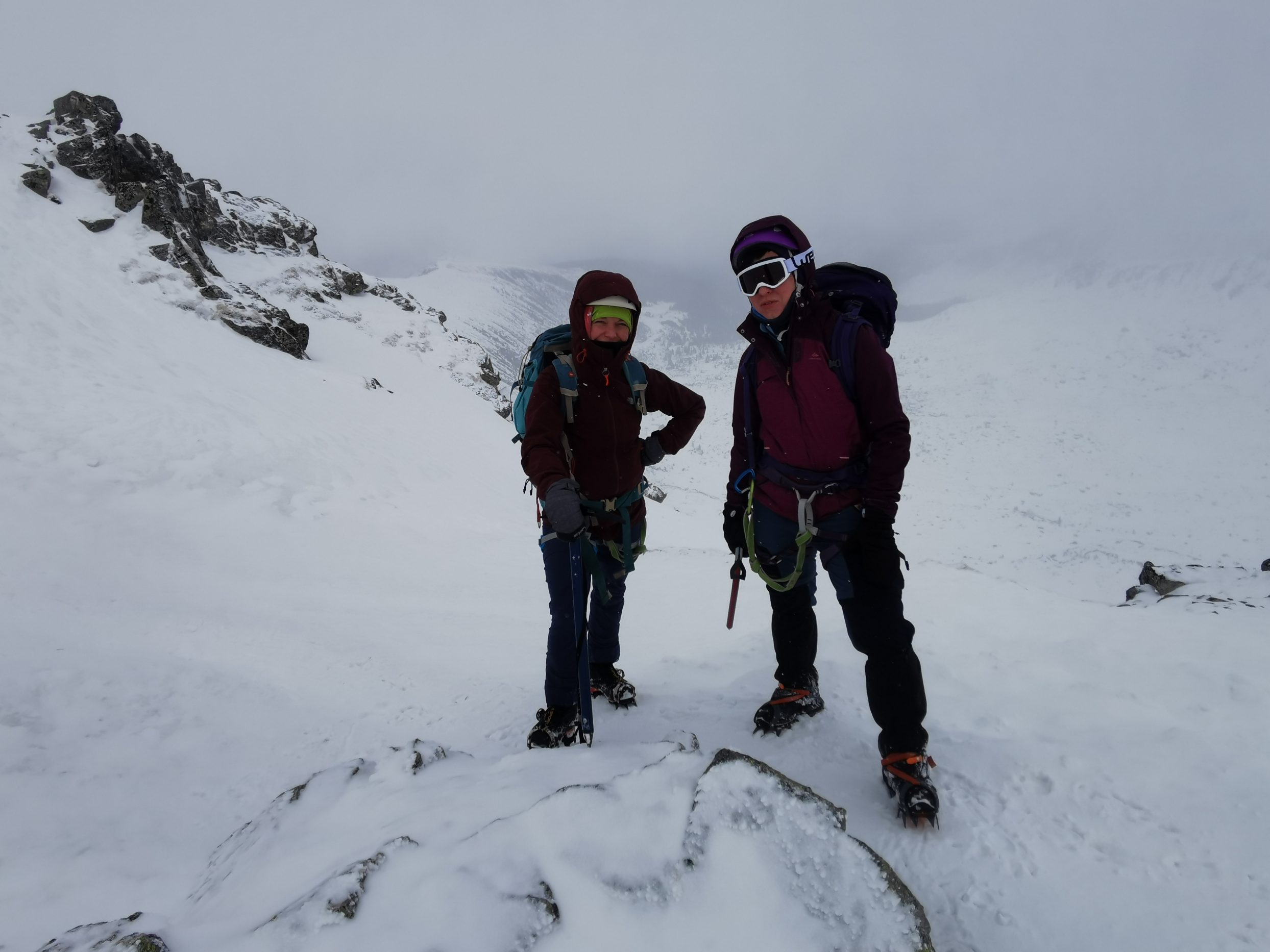 Alpinista i alpinistka stoją w górach w zimowej scenerii.