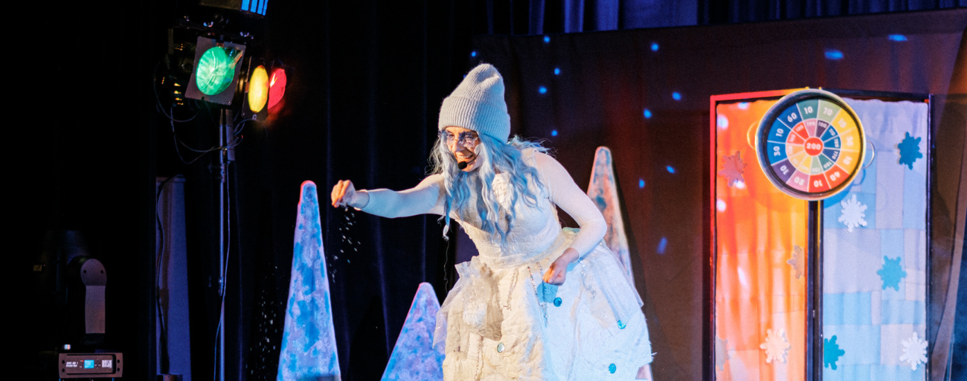 Aktorka przebrana za śnieżynkę sypiąca "śnieg" w stronę publiczności.