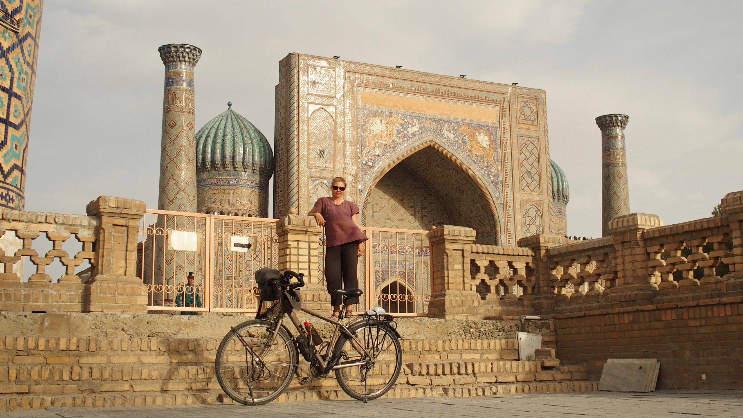Kobieta z rowerem na tle budowli w Uzbekistanie.